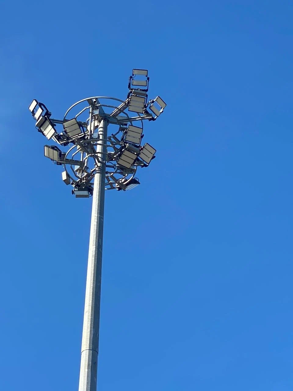 High-mast pole supporting a circular arrangement of floodlights.