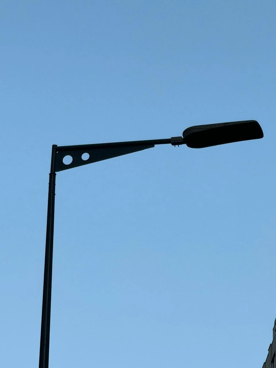 Street-lighting bracket extending from a steel pole to a luminaire.
