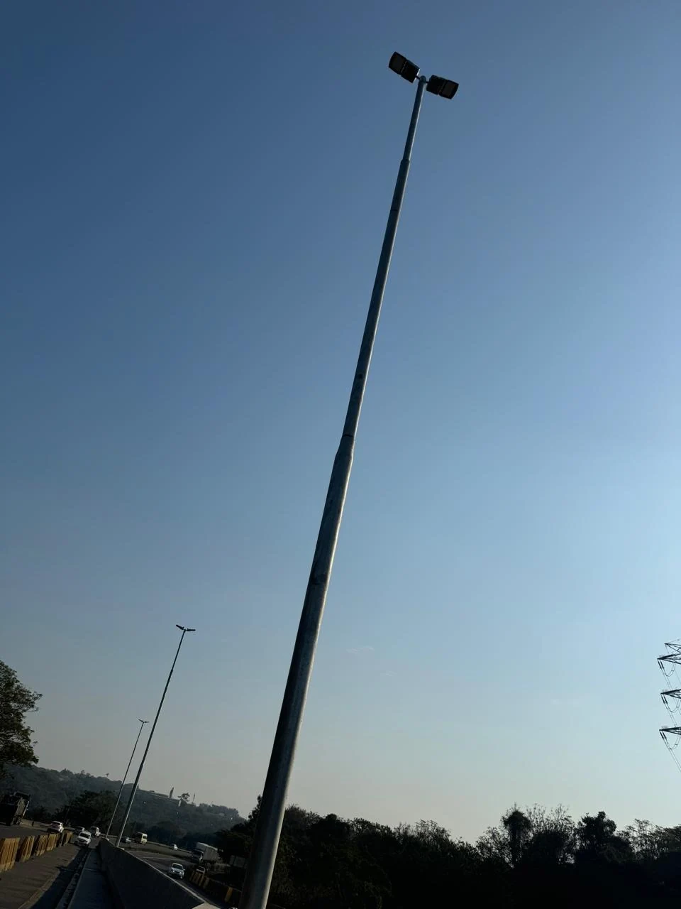 Tall roadway lighting pole beside a divided road.